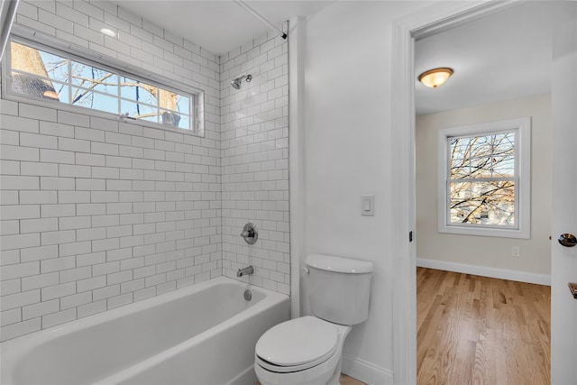 bathroom with tiled shower / bath combo, hardwood / wood-style flooring, and toilet