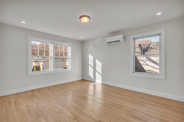 unfurnished room with an AC wall unit and light hardwood / wood-style flooring