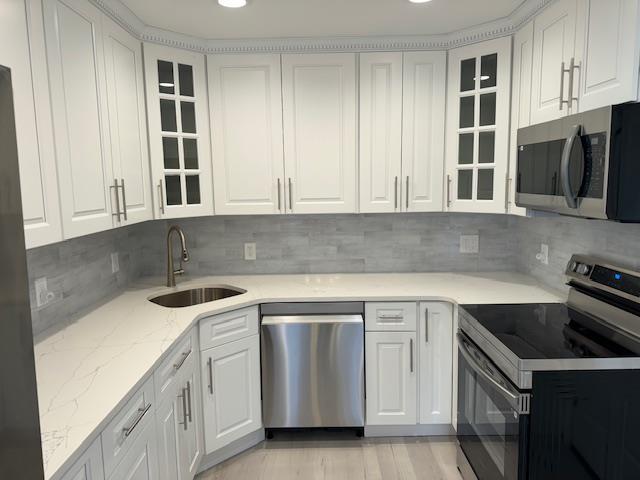 kitchen with white cabinets, backsplash, sink, and stainless steel appliances