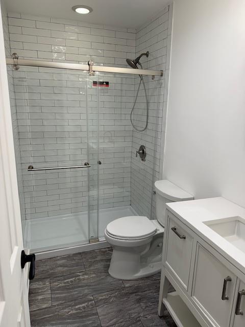 bathroom with vanity, toilet, and a shower with door