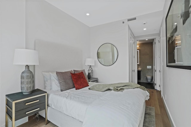 bedroom featuring dark hardwood / wood-style flooring and ensuite bath