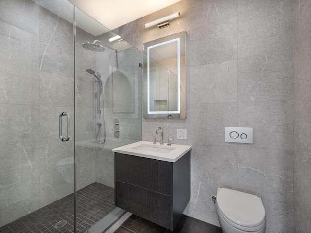 bathroom featuring vanity, a shower with door, toilet, and tile walls