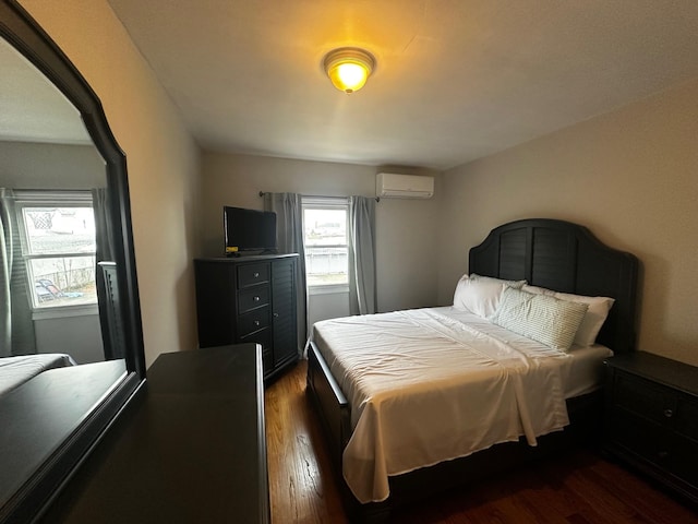 bedroom with dark hardwood / wood-style floors and a wall mounted air conditioner