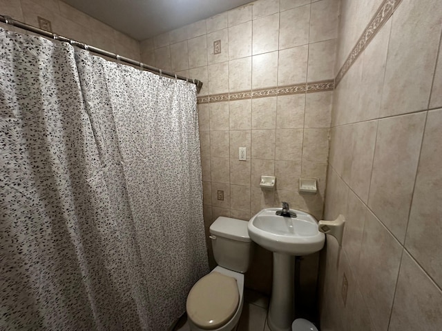 bathroom featuring walk in shower, toilet, and tile walls