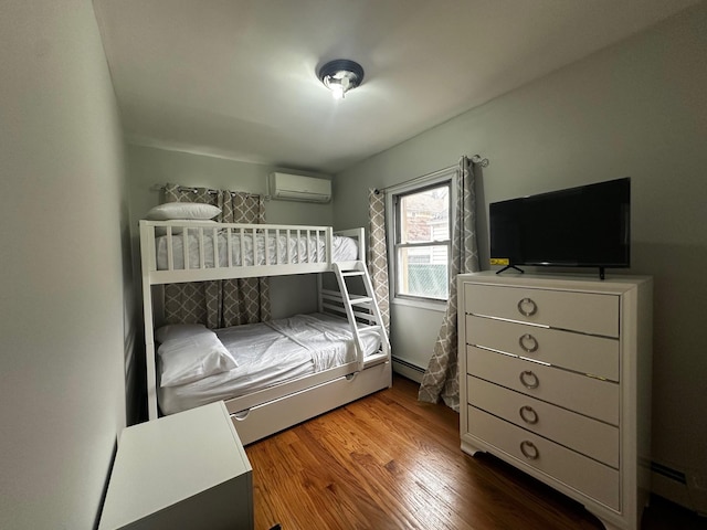 bedroom featuring hardwood / wood-style flooring and an AC wall unit