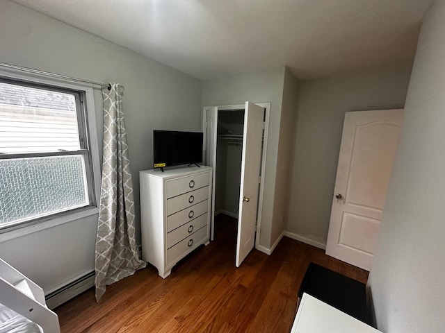 bedroom with a closet, dark hardwood / wood-style flooring, and a baseboard radiator