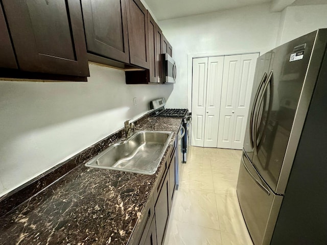 kitchen with dark stone countertops, dark brown cabinetry, sink, and appliances with stainless steel finishes