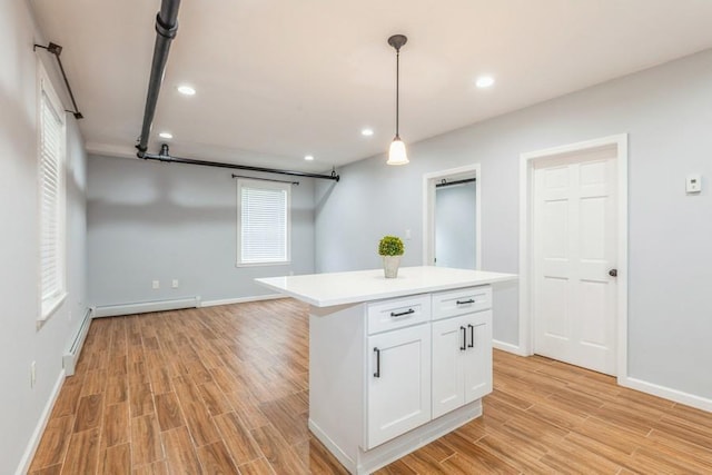 kitchen with a center island, light wood-type flooring, decorative light fixtures, and white cabinetry