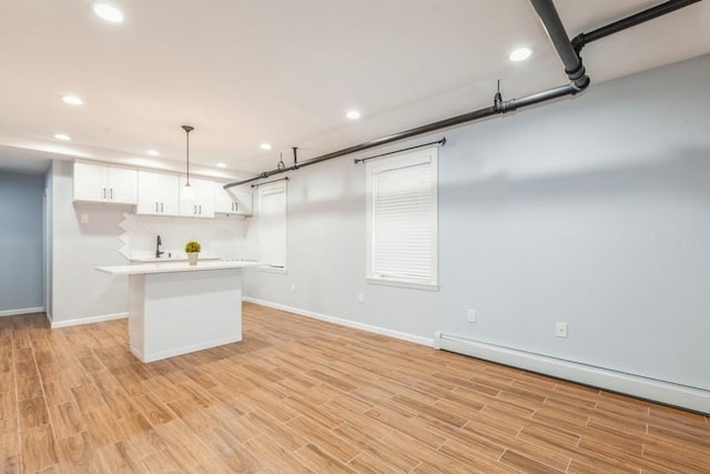 kitchen featuring pendant lighting, light wood-type flooring, white cabinetry, and a baseboard heating unit