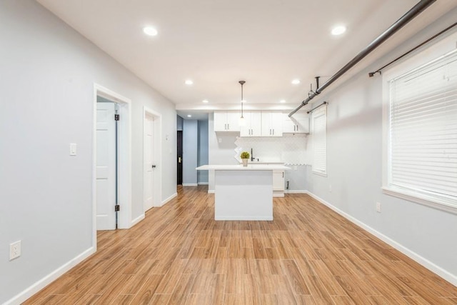 kitchen featuring white cabinetry, a center island, pendant lighting, and light wood-type flooring