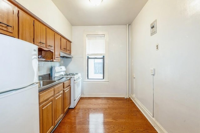 kitchen featuring dark hardwood / wood-style floors, white appliances, and sink