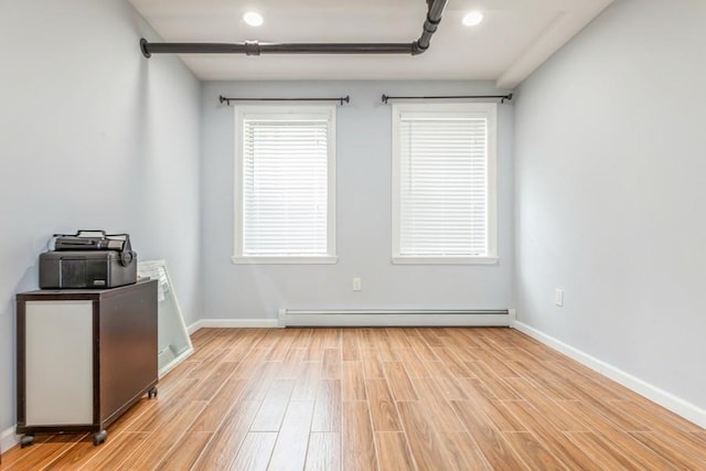 unfurnished room featuring a baseboard radiator and light hardwood / wood-style flooring