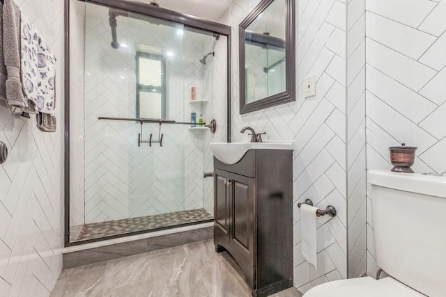 bathroom featuring vanity, toilet, a shower with shower door, and tile walls