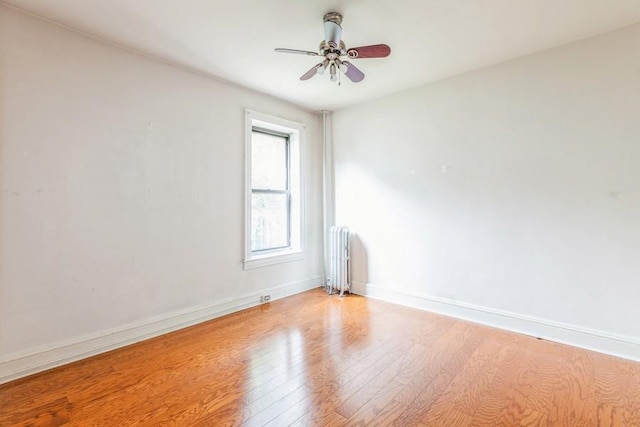 empty room featuring light hardwood / wood-style flooring, radiator, and ceiling fan