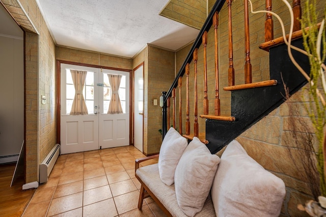 foyer entrance with french doors, a textured ceiling, ornamental molding, and a baseboard heating unit