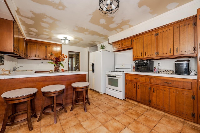 kitchen featuring white appliances, sink, light tile patterned floors, a kitchen bar, and kitchen peninsula