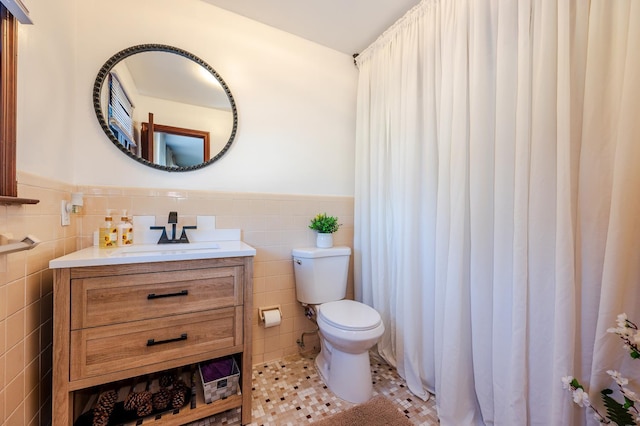 bathroom featuring tile patterned floors, vanity, toilet, and tile walls