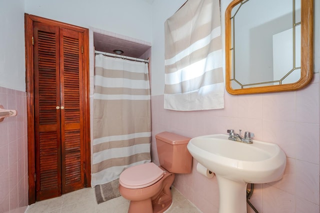 bathroom featuring tile patterned flooring, tile walls, and toilet