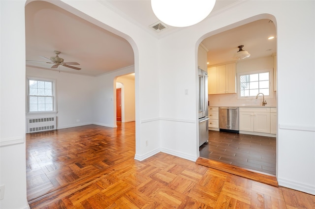 interior space featuring light parquet floors, sink, ceiling fan, ornamental molding, and radiator heating unit