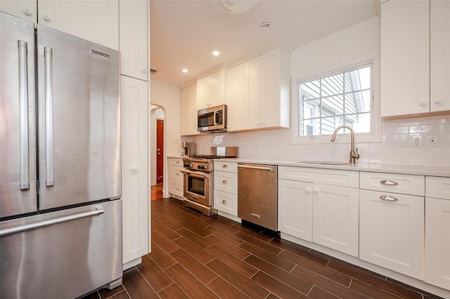 kitchen with dark wood-type flooring, white cabinets, sink, tasteful backsplash, and premium appliances