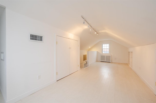 additional living space featuring light hardwood / wood-style flooring, lofted ceiling, and radiator heating unit