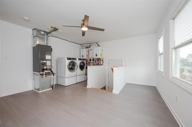 laundry room with washer and clothes dryer, ceiling fan, water heater, wood-type flooring, and heating unit