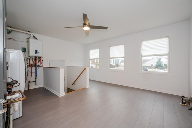 unfurnished room with hardwood / wood-style floors, ceiling fan, and water heater