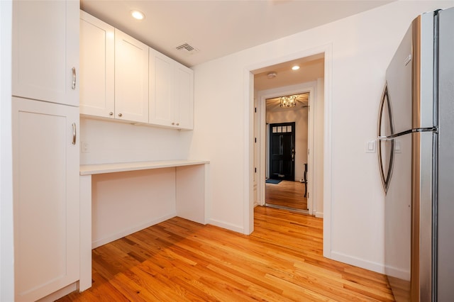 kitchen featuring white cabinetry, stainless steel refrigerator, and light hardwood / wood-style flooring