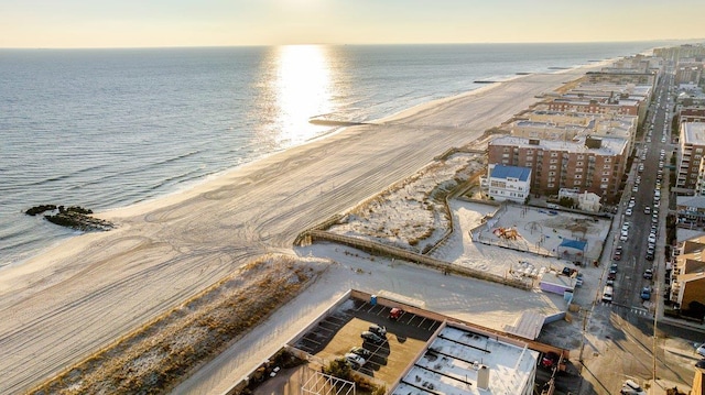 aerial view at dusk with a water view and a view of the beach