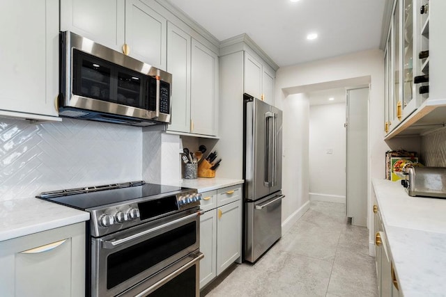 kitchen featuring tasteful backsplash, light stone countertops, appliances with stainless steel finishes, and light tile patterned floors