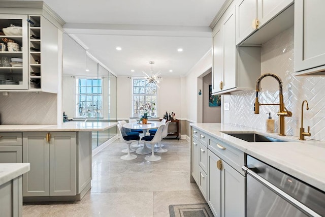 kitchen with light stone counters, stainless steel dishwasher, sink, and gray cabinetry