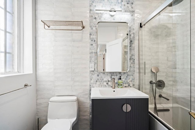 full bathroom with vanity, combined bath / shower with glass door, tile walls, and toilet