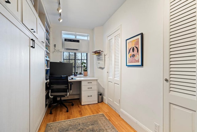 office area with a wall mounted air conditioner, rail lighting, and light wood-type flooring