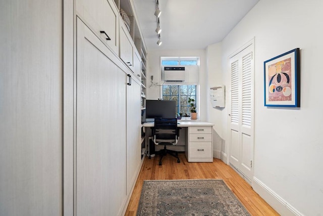 office area featuring a wall mounted air conditioner, rail lighting, and light hardwood / wood-style floors