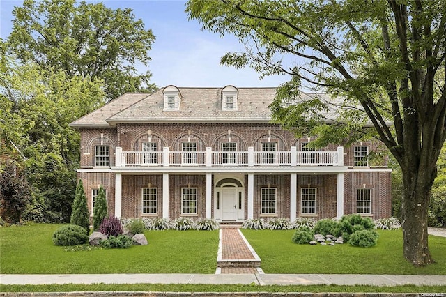 view of front of property featuring a front lawn, a balcony, and covered porch