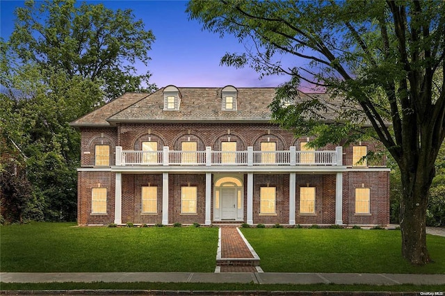 view of front of property with a balcony, covered porch, and a lawn