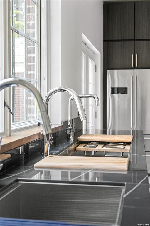 interior details featuring high end fridge, sink, and dark brown cabinetry