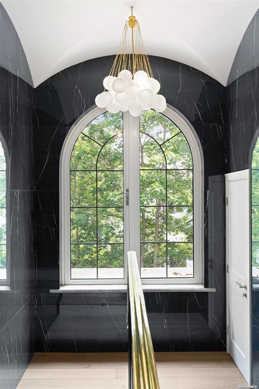 stairway featuring lofted ceiling, a notable chandelier, and hardwood / wood-style flooring