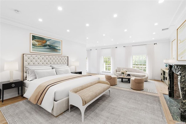 bedroom featuring a fireplace, ornamental molding, and light hardwood / wood-style floors