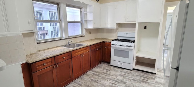 kitchen with light stone countertops, sink, backsplash, white appliances, and white cabinets