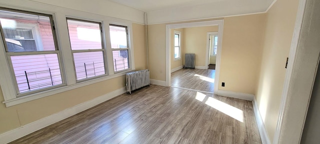 spare room featuring radiator heating unit and light hardwood / wood-style floors