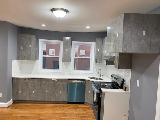 kitchen featuring exhaust hood, sink, light hardwood / wood-style floors, and appliances with stainless steel finishes