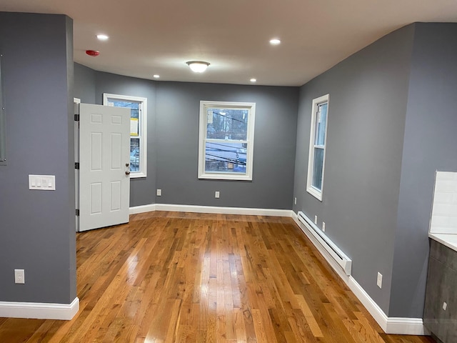 empty room with light hardwood / wood-style floors and a baseboard heating unit