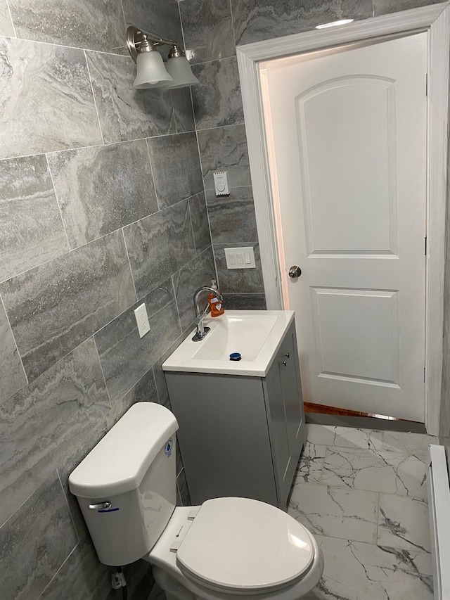 bathroom with vanity, toilet, and tile walls