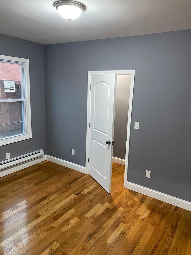 unfurnished room with wood-type flooring and a baseboard radiator