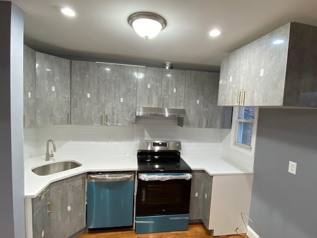 kitchen with appliances with stainless steel finishes, gray cabinets, light hardwood / wood-style flooring, and sink