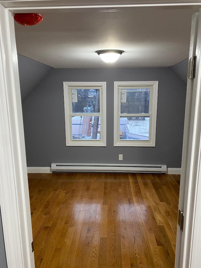 additional living space featuring baseboard heating, lofted ceiling, and hardwood / wood-style flooring