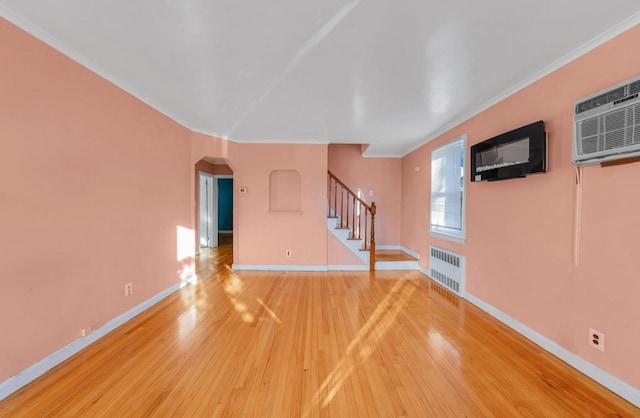 unfurnished living room with hardwood / wood-style flooring, a wall unit AC, ornamental molding, and radiator