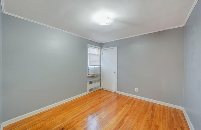 empty room with radiator, ornamental molding, and light wood-type flooring