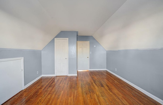 bonus room with dark hardwood / wood-style flooring and vaulted ceiling